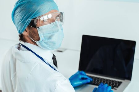 A doctor wear protective gloves when using the laptop