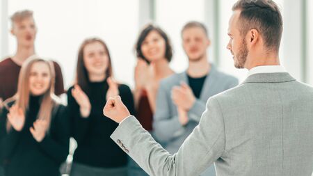 Businessman standing in front of applauding business team