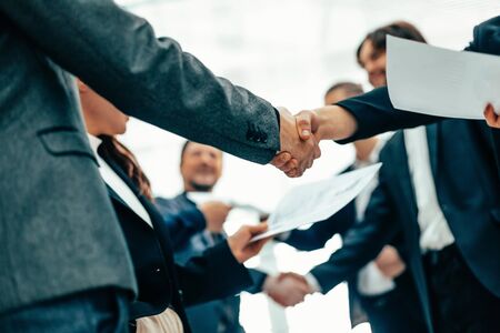A group of employees shaking hands at an office meeting.