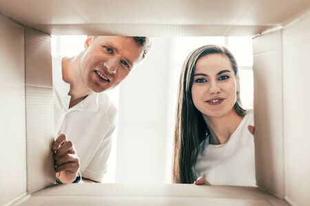 beautiful couple looks into a large cardboard box.の写真素材