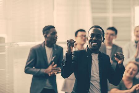 happy guy and a group of young business people are cheering in the officeの写真素材