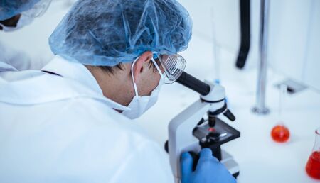 close up. scientist looking through a microscope.