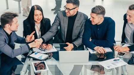 close up. business colleagues shaking hands over an office Desk.