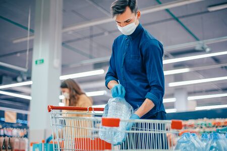 shoppers in protective masks choosing products in the supermarket.の写真素材