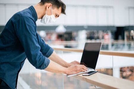 close up. a young man in a protective mask using a laptopの写真素材