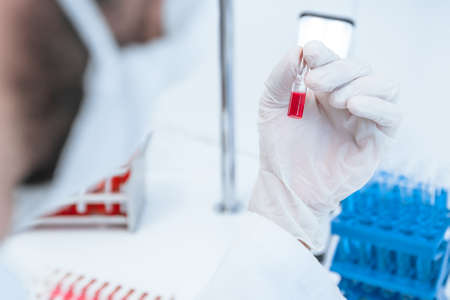 close up. medical scientist holds an ampoule with a new vaccine.の写真素材