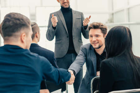 smiling employees shaking hands during a working meeting