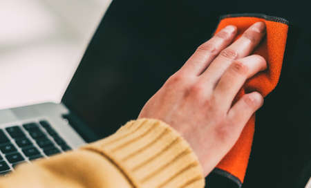 woman spraying antiseptic on the surface of a laptop.の写真素材