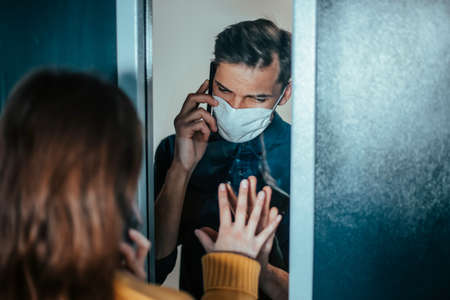 young man and a woman are looking at each other anxiously through the glass.