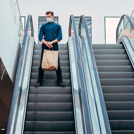 lone man in a protective mask standing on the escalator stepsの写真素材