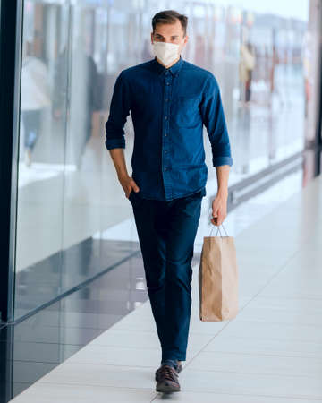 man in a protective mask passing near a supermarket.の写真素材