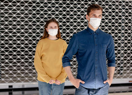 man and a woman in protective masks standing at a safe distance .の写真素材