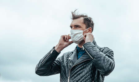 young man putting on a protective mask standing on the street