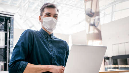young blogger in protective mask looking through the window