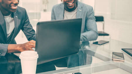 smiling colleagues looking at work on a laptop in the office.の写真素材