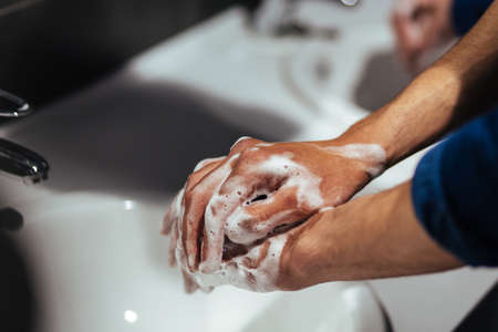 close up. young man soaping his hands under the tap