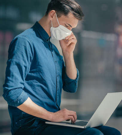 young man in a protective mask talking on a smartphone.の写真素材