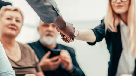 businessman and businesswoman shaking hands over the meeting table.