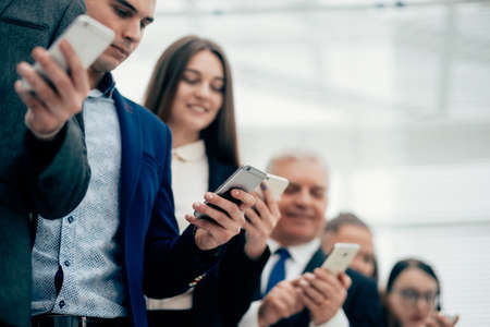 group of smiling business people looking at their smartphone screensの写真素材