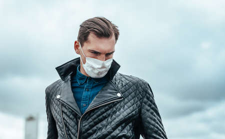 man in a protective mask looks at the empty streetの写真素材