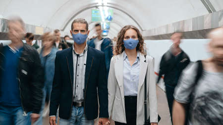 man and a woman in protective masks walking along the platform in subway .の写真素材