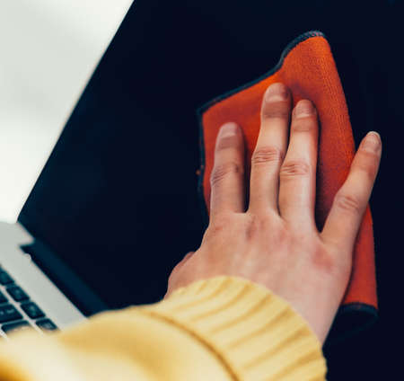woman spraying antiseptic on the surface of a laptop.の写真素材