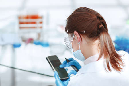 Young woman scientist using smartphone in the laboratory