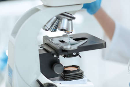close up. Scientist analyzing microscope slide at laboratory.