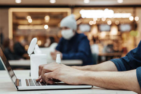 image of a young man working on a laptop in a public place