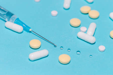 syringe and various pills on a blue background.の写真素材