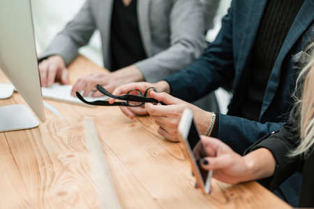 close up. employees with smart devices sitting at the Deskの写真素材