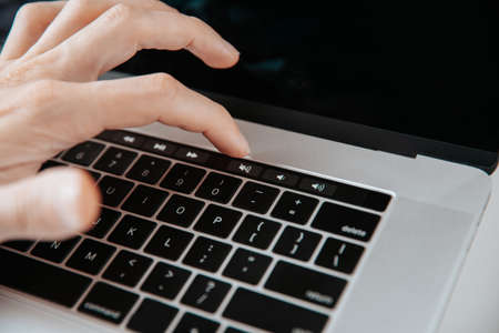 close up. man turning off the sound on his laptop.
