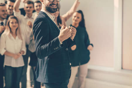 happy business man standing in front of his team.の写真素材