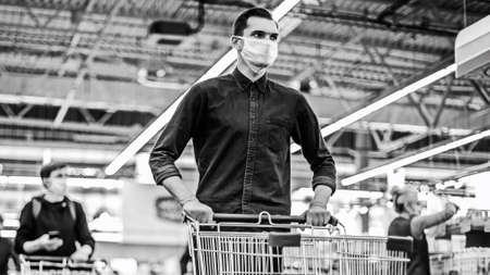 young man in a protective mask with a shopping cartの写真素材