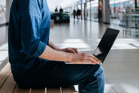 man in protective mask using a laptop on a city street