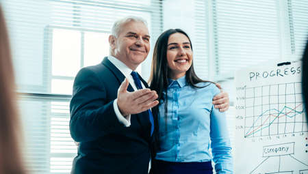 boss and young speaker standing together in front of business presentation listenersの写真素材