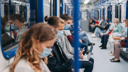 passengers in protective masks using their gadgets in the subway car .の写真素材
