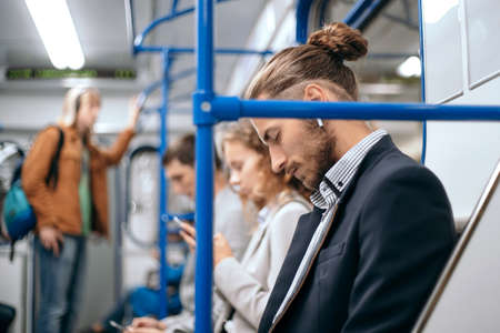 tired business man sleeps in a subway train car.の写真素材