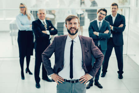 smiling business man standing in front of the business teamの写真素材