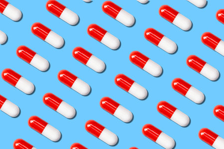 lot of red and white medical capsules on a blue background.の写真素材