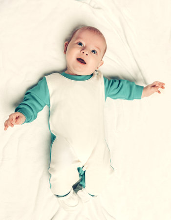 cute kid in a penguin suit lying on a blanket.の写真素材