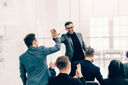 happy colleagues giving each other a high five .の写真素材