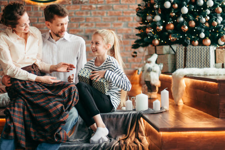parents with their young children sitting in the living room decorated for Christmasの写真素材