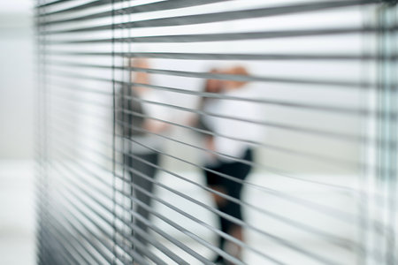through the blinds. a group of business women talking in the office lobbyの写真素材