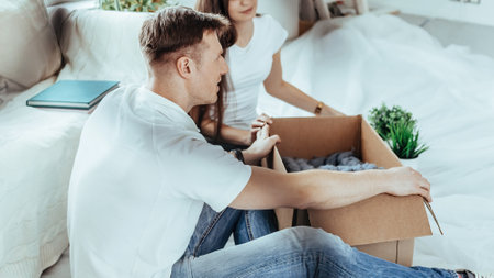 couple opening a cardboard box in a new apartment .の写真素材
