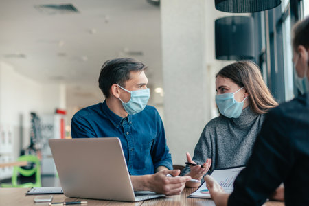 business colleagues in protective masks sitting at the office Desk.の写真素材