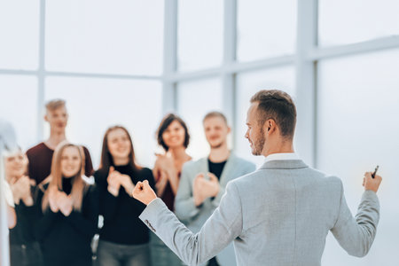 rear view. business man standing in front of applauding business teamの写真素材