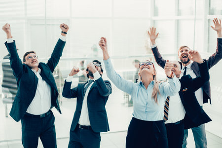 happy business woman standing in front of a cheering business team.の写真素材
