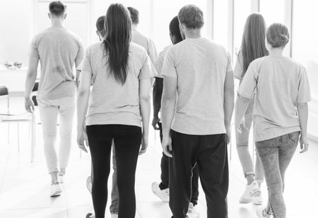 rear view. a group of young people standing in a bright roomの写真素材