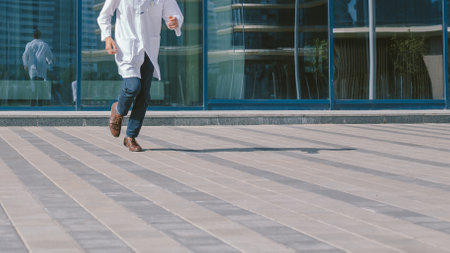 doctor with a stethoscope runs quickly along a city street.の写真素材